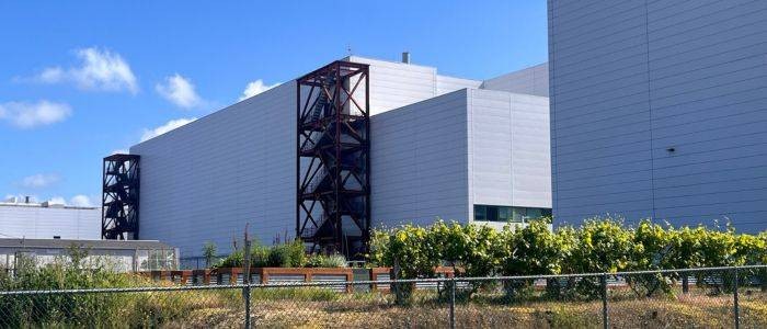 garden boxes behind a fence with a large industrial building in the background